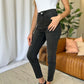 Woman wearing RFM Full Size High Rise Tummy Control Skinny Jeans in black, paired with a white tank top and black sneakers.