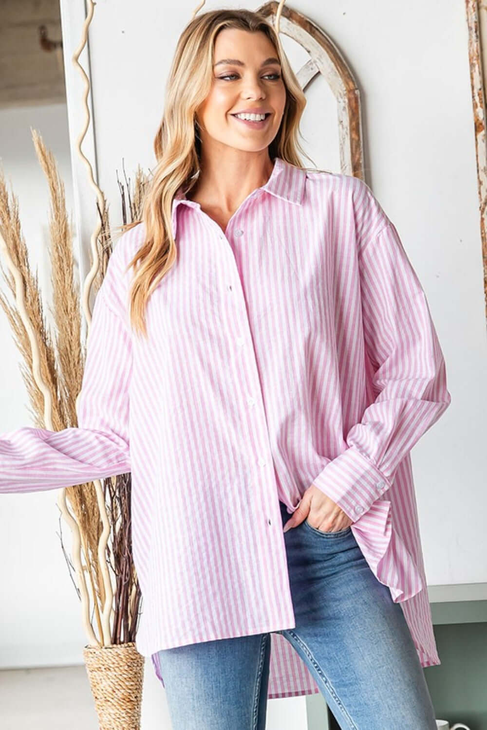 Woman wearing First Love Full Size Striped Button Down High-Low Hem Shirt in pink and white stripes with jeans.