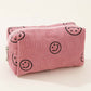 Pink corduroy cosmetic pouch with smiley face design, perfect for organizing makeup essentials on the go.