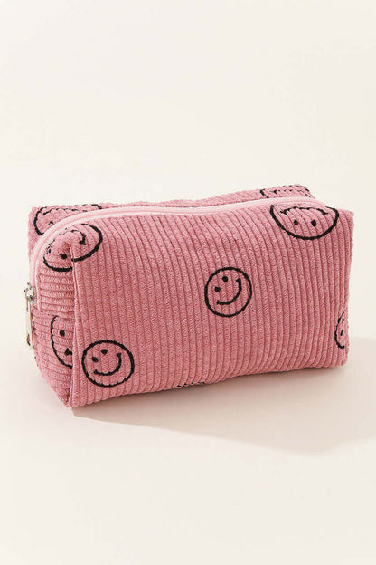 Pink corduroy cosmetic pouch with smiley face design, perfect for organizing makeup essentials on the go.