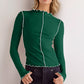 Model in a green mock neck long sleeve t-shirt with contrast trim, styled with dark jeans.