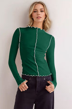 Model in a green mock neck long sleeve t-shirt with contrast trim, styled with dark jeans.