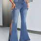 Woman wearing stylish slit flare jeans with pockets and flared leg opening, standing in a modern room. Highly stretchy denim, perfect for any occasion.