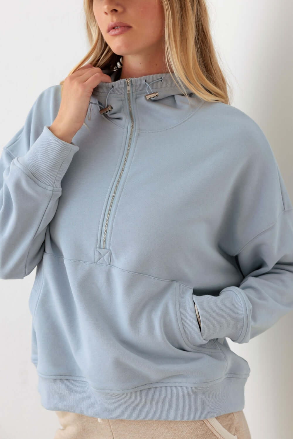 Woman wearing Tasha Apparel Half Zip Drawstring Mock Neck Hoodie in solid color with long sleeves and a front pocket.