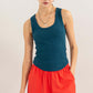 Woman wearing Ribbed Scoop Neck Racerback Tank in teal, paired with red pants, showcasing a stylish and comfortable fit.