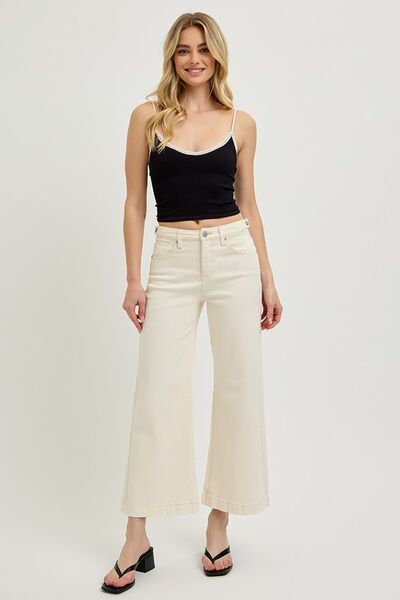 Model wearing wide-leg cream jeans with a black tank top and stylish sandals, showcasing a trendy summer outfit.