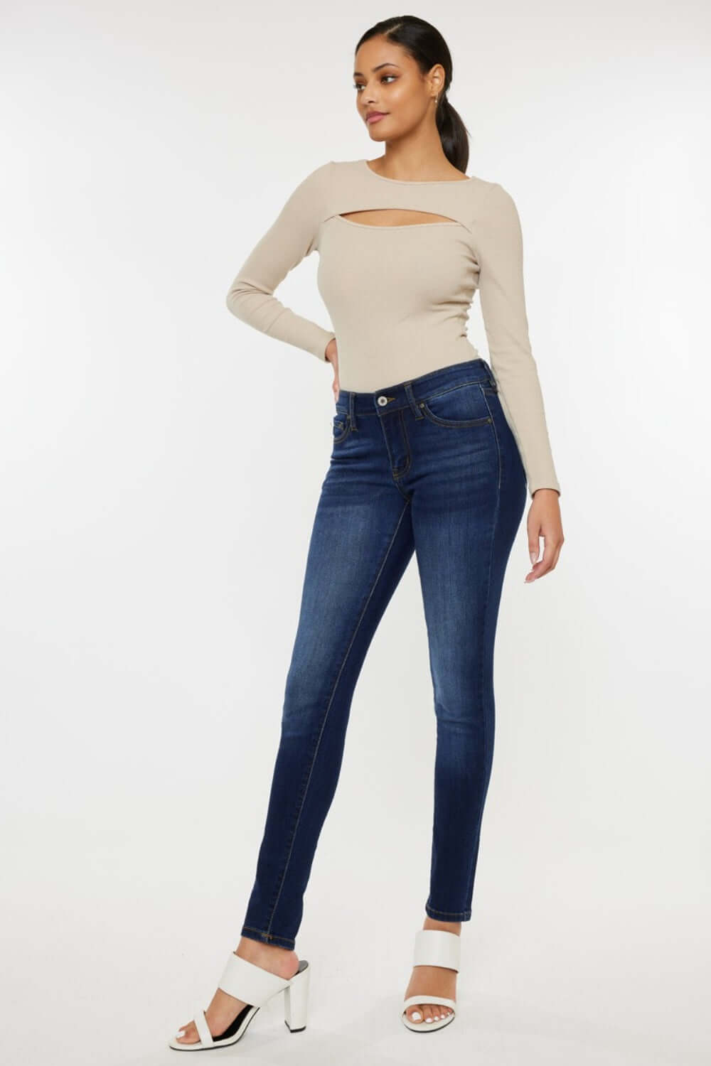 Woman modeling mid-rise gradient skinny jeans with a stylish top and white heels, showcasing a trendy and flattering look.