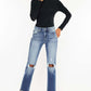 Woman modeling high waist distressed hem detail cropped straight jeans with edgy, worn-in look, paired with black top and sneakers