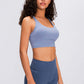 Model showcasing the Millennia Double X Sports Bra in blue, featuring a supportive design and stylish strappy back.