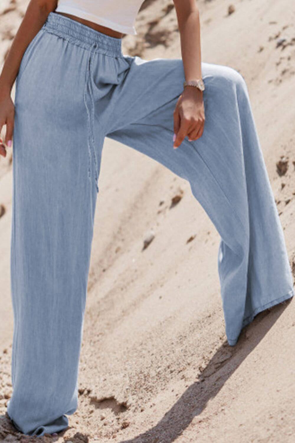 Model showcasing Bella Road Drawstring Wide Leg Jeans in medium blue, highlighting comfort and trendy style on sandy terrain.