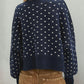 Woman wearing Bella Road Slit Round Neck Long Sleeve Sweater in navy with white patterns, paired with brown pants.