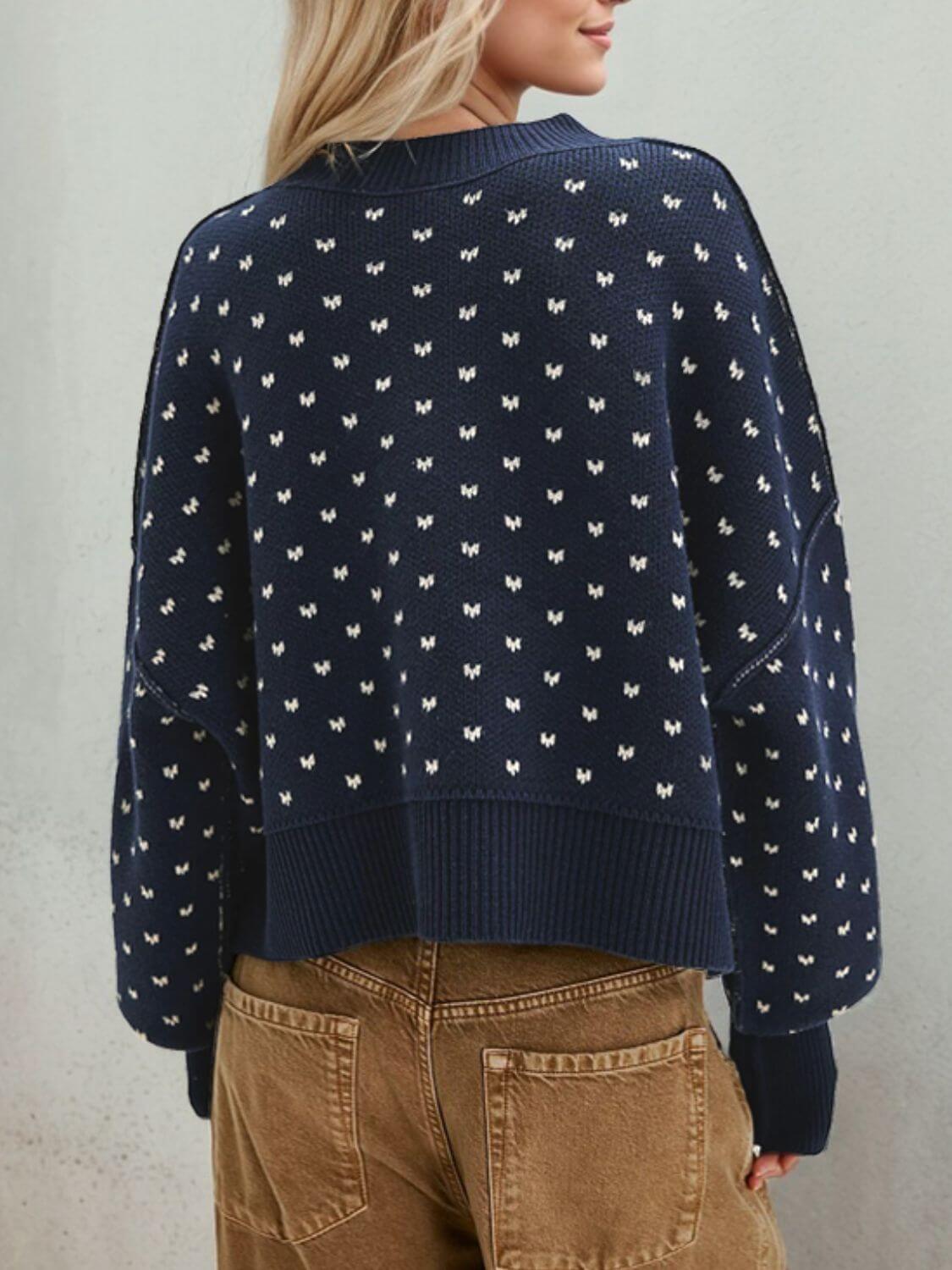 Woman wearing Bella Road Slit Round Neck Long Sleeve Sweater in navy with white patterns, paired with brown pants.