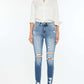 Woman wearing High Rise Frayed Ankle Skinny Jeans in medium wash with distressed detailing and fray hem, paired with white shirt and heels.