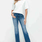 Stylish woman in distressed high rise jeans and white top, showcasing a trendy and comfortable look with pockets.