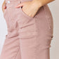 Woman wearing Risen Jeans high-rise ankle flare jeans in a stylish pink color, showcasing the flattering fit and versatile pockets.