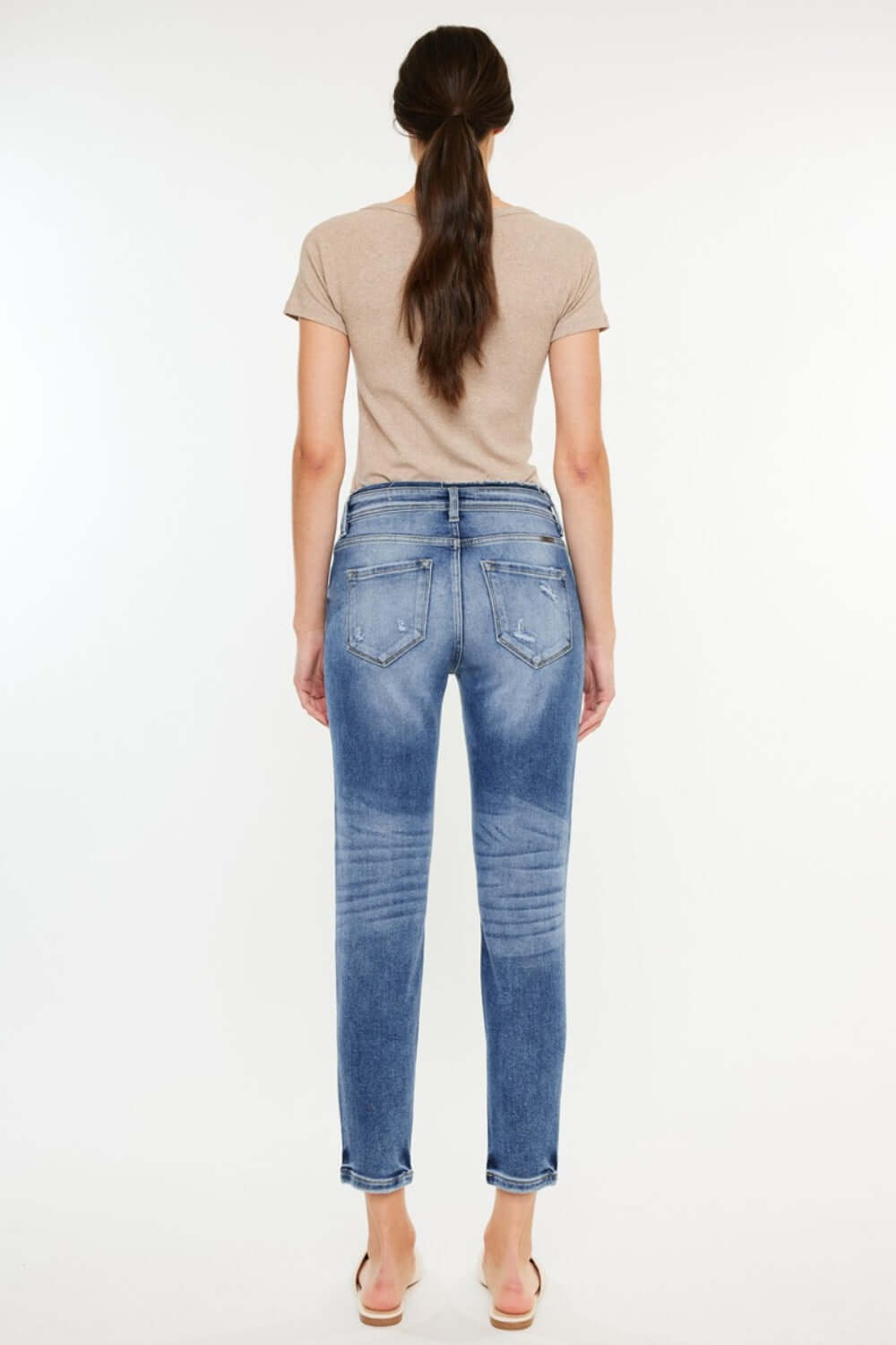 Back view of High Rise Distressed Mom Jeans showcasing flattering high-rise waist and distressed detailing, paired with beige top.