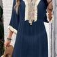 Woman wearing a navy fringe tie neck cover-up with three-quarter sleeves and intricate embroidery detailing.