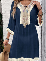 Woman wearing a navy fringe tie neck cover-up with three-quarter sleeves and intricate embroidery detailing.