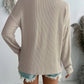 Beige textured V-neck long sleeve T-shirt with pockets, seen from the back, worn with frayed denim shorts, perfect for casual wear.