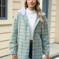 Woman wearing Bella Road Drawstring Plaid Long Sleeve Hooded Jacket in beige and blue outside of a building