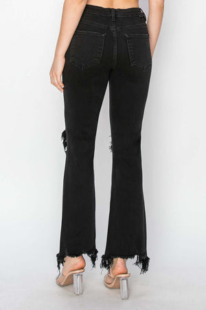 Woman in Risen Jeans, black distressed raw hem jeans with pockets and unique ripped design. Trendy everyday and casual wear for eye-catching style.