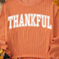 Bella Road THANKFUL round neck long sleeve sweatshirt, orange color, autumn-themed background with leaves, pinecones, and pumpkins.