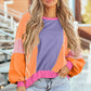 Woman wearing Bella Road Color Block Round Neck Long Sleeve Top with trendy color block design and casual denim shorts.