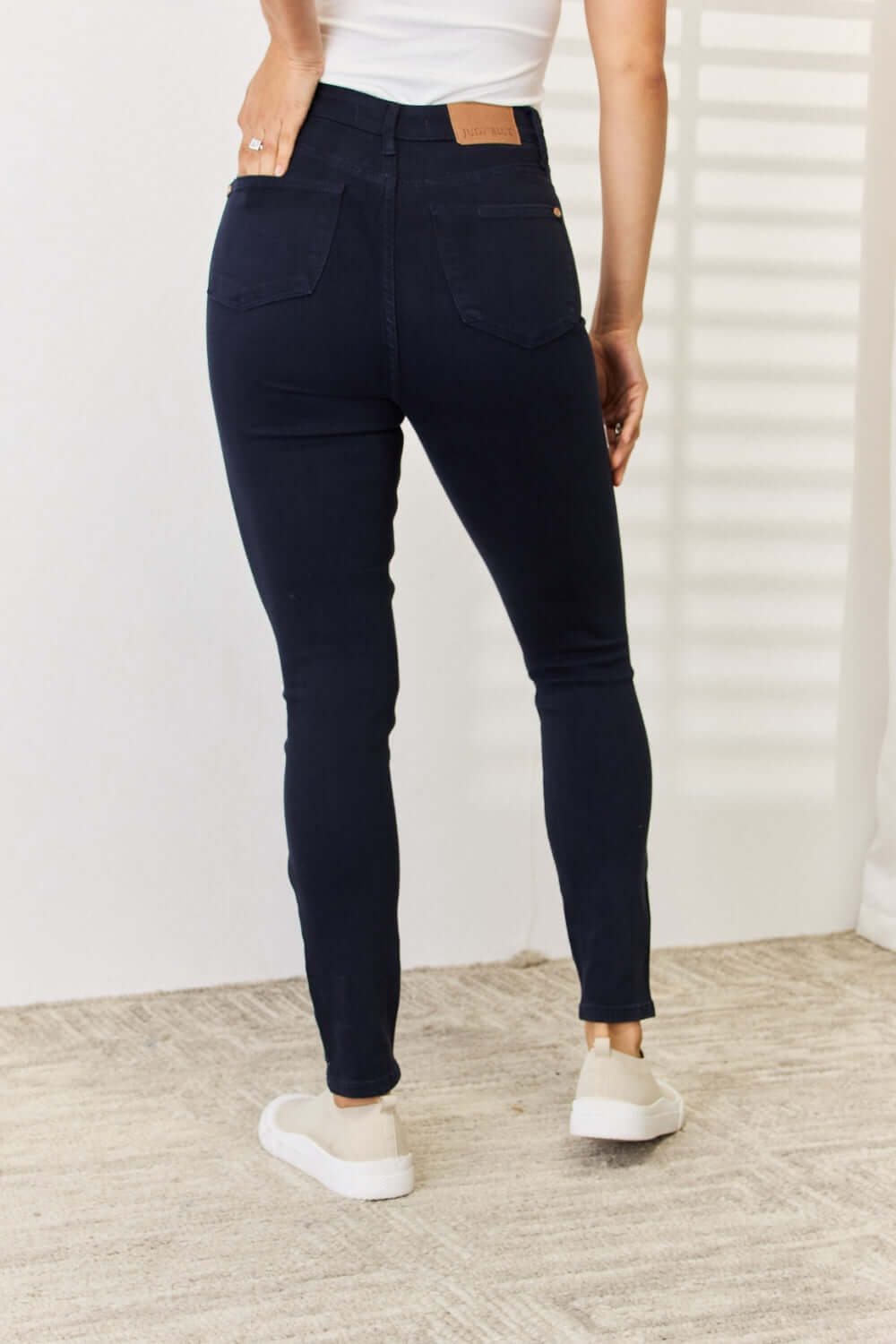 Back view of woman wearing Garment Dyed Tummy Control Skinny Jeans by Judy Blue Jeans showing off slimming silhouette.