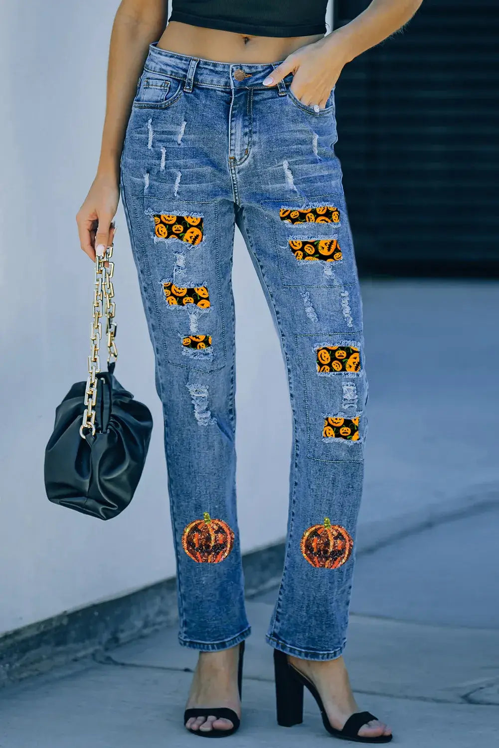 Woman wearing Pumpkin Distressed Straight Jeans with sequin details and a black handbag