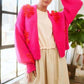 Model showcasing a vibrant pink floral applique cardigan over a casual cream dress, perfect for layered looks.