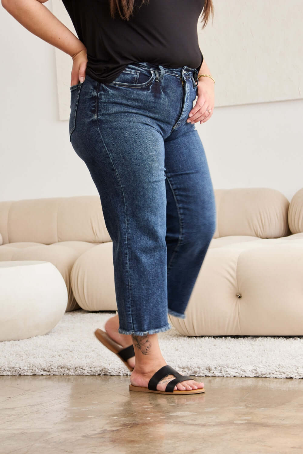 Woman wearing Tummy Control High Waist Raw Hem Jeans from RFM Jeans, showcasing a stylish and flattering fit with distressed and trendy raw hem detailing.