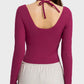 Back view of a woman wearing a fuchsia Millennia halter neck sporty top with long sleeves, showcasing its stylish design.