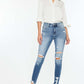 Woman wearing High Rise Frayed Ankle Skinny Jeans in medium wash with distressed detailing and fray hem, paired with a white button-up shirt.