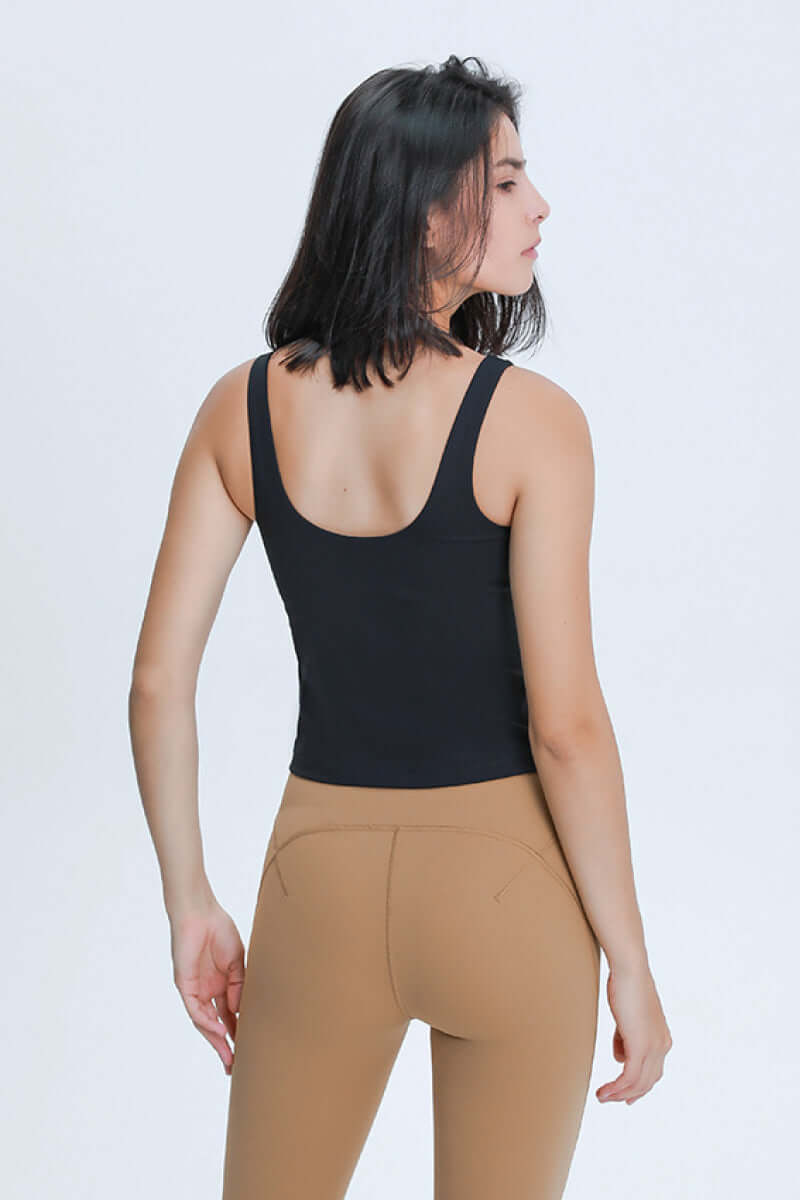 Woman in sleek black v neck active tank top and leggings, showcasing a stylish workout look from the back.