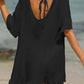 Woman wearing black tied ruffled half sleeve cover-up on beach, back view