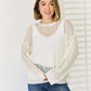 Woman wearing an Openwork Ribbed Trim Long Sleeve Knit Top in white paired with blue jeans, showcasing the stylish and modern design