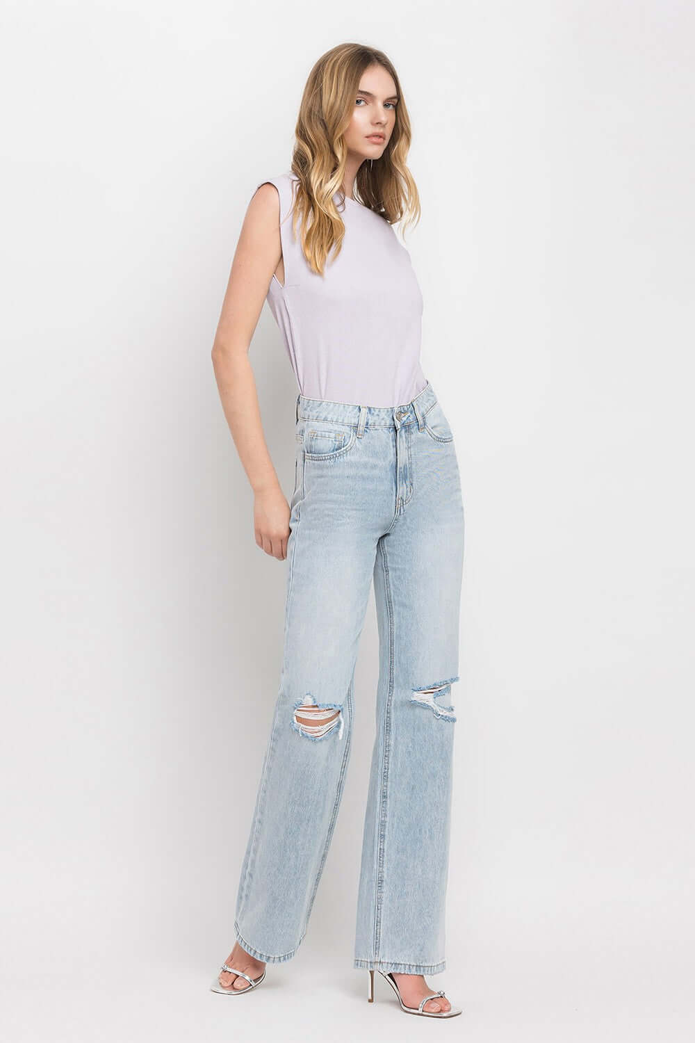 Woman wearing 90's Vintage Super High Rise Flare Jeans with a super high-rise waist and wide flare legs, paired with a sleeveless top.