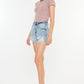 Model wearing Kancan distressed high waist denim shorts with pockets and a stylish knit top.