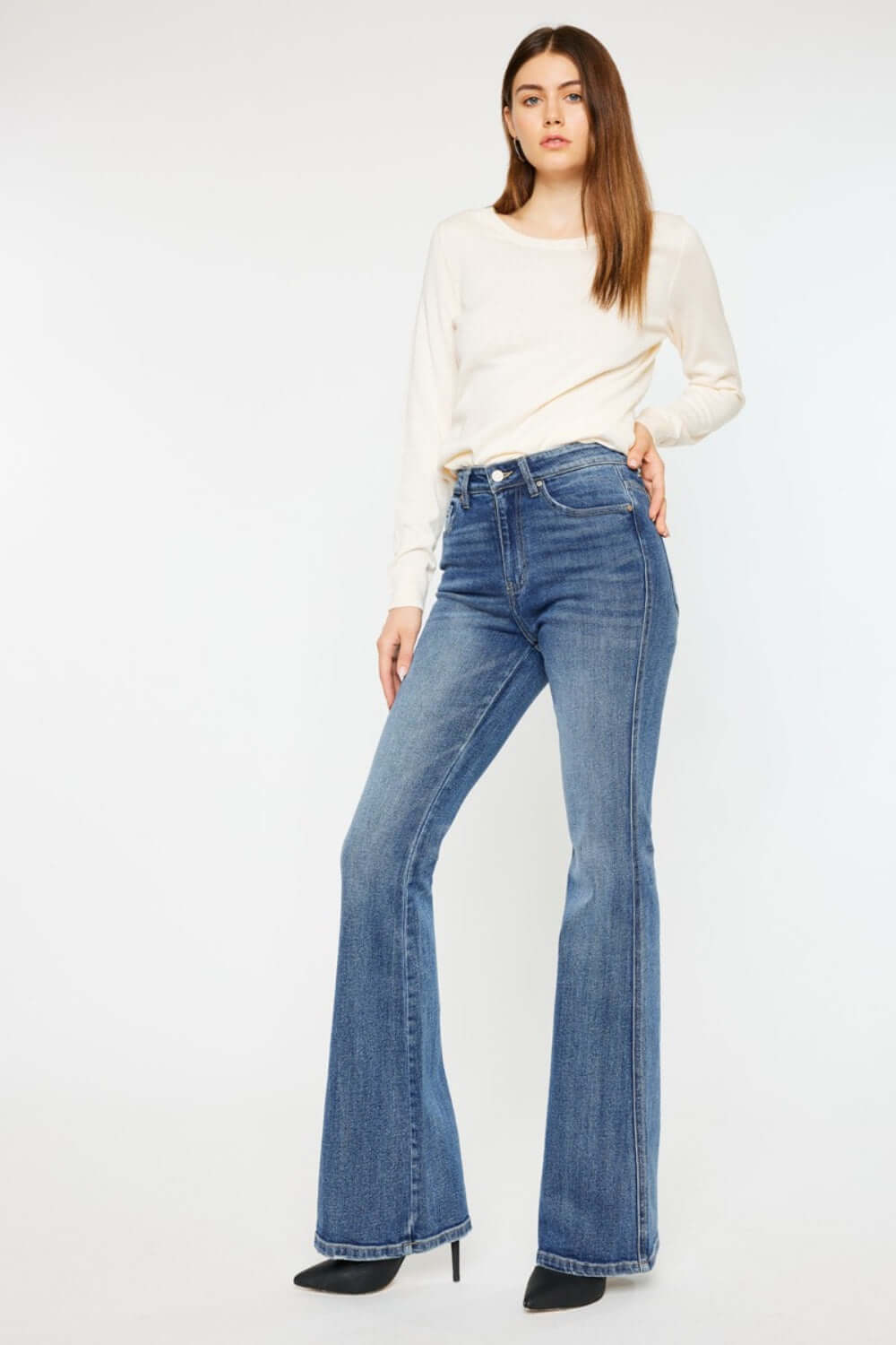 Model wearing Cat's Whiskers High Waist Flare Jeans with white top and black heels for a chic, retro-inspired look.