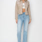 Plus size woman wearing a cropped button-up denim jacket with raw hem, paired with light wash flared jeans.