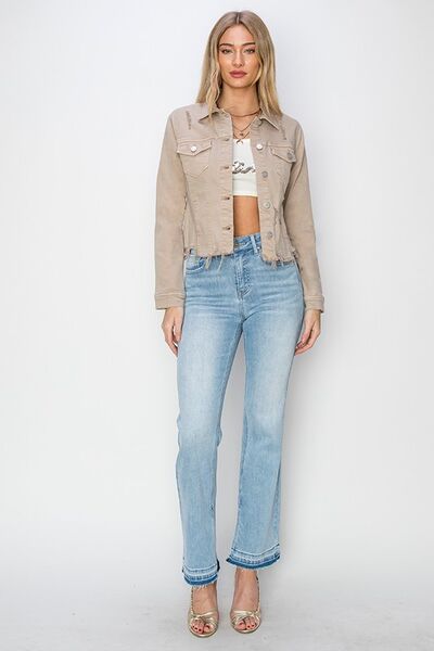 Plus size woman wearing a cropped button-up denim jacket with raw hem, paired with light wash flared jeans.