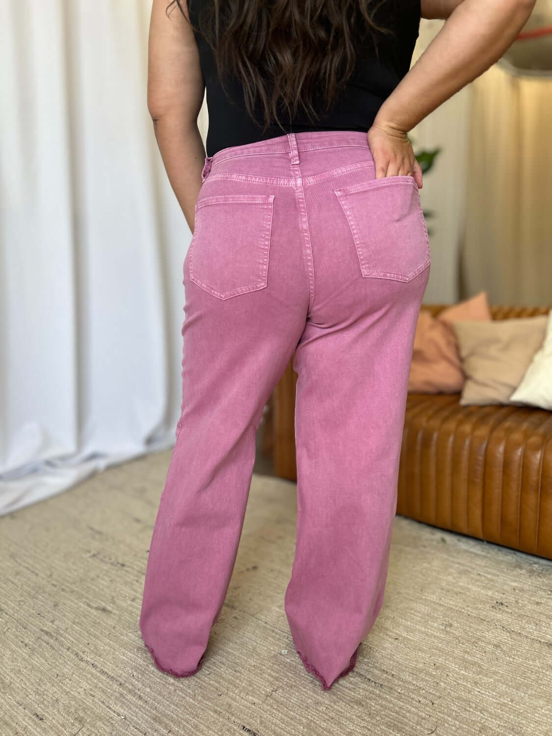 Back view of woman wearing RFM Full Size High Rise Garment Dye Wide Leg Jeans in rich pink color, highlighting relaxed fit and two back pockets.