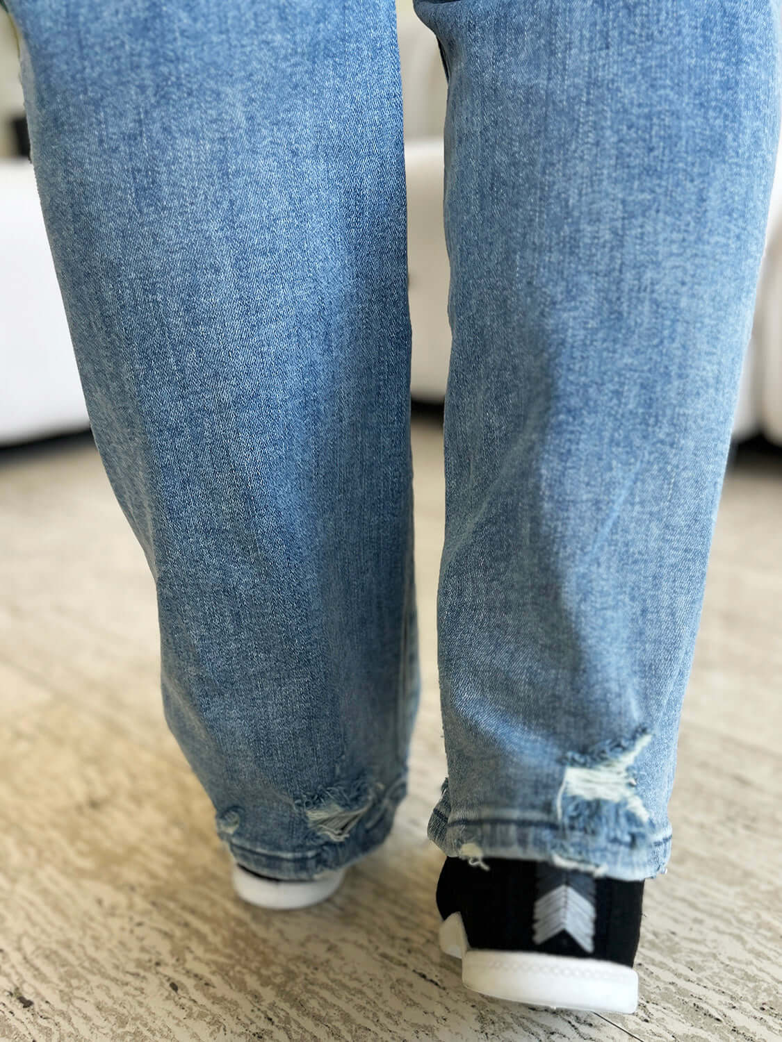 Close-up of back view of person wearing High Waist Distressed Straight Jeans by Judy Blue Jeans showing distressed detailing.