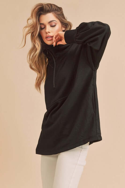 Stylish woman in a black exposed seam half zip drop shoulder sweatshirt, perfect for casual and trendy outfits.