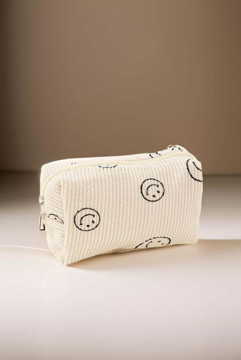 Cute cream corduroy cosmetic pouch with smiley face design, perfect for organizing makeup essentials on-the-go.