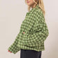 Stylish woman in green tweed plaid button-up jacket, showcasing a modern collared neck and relaxed fit.