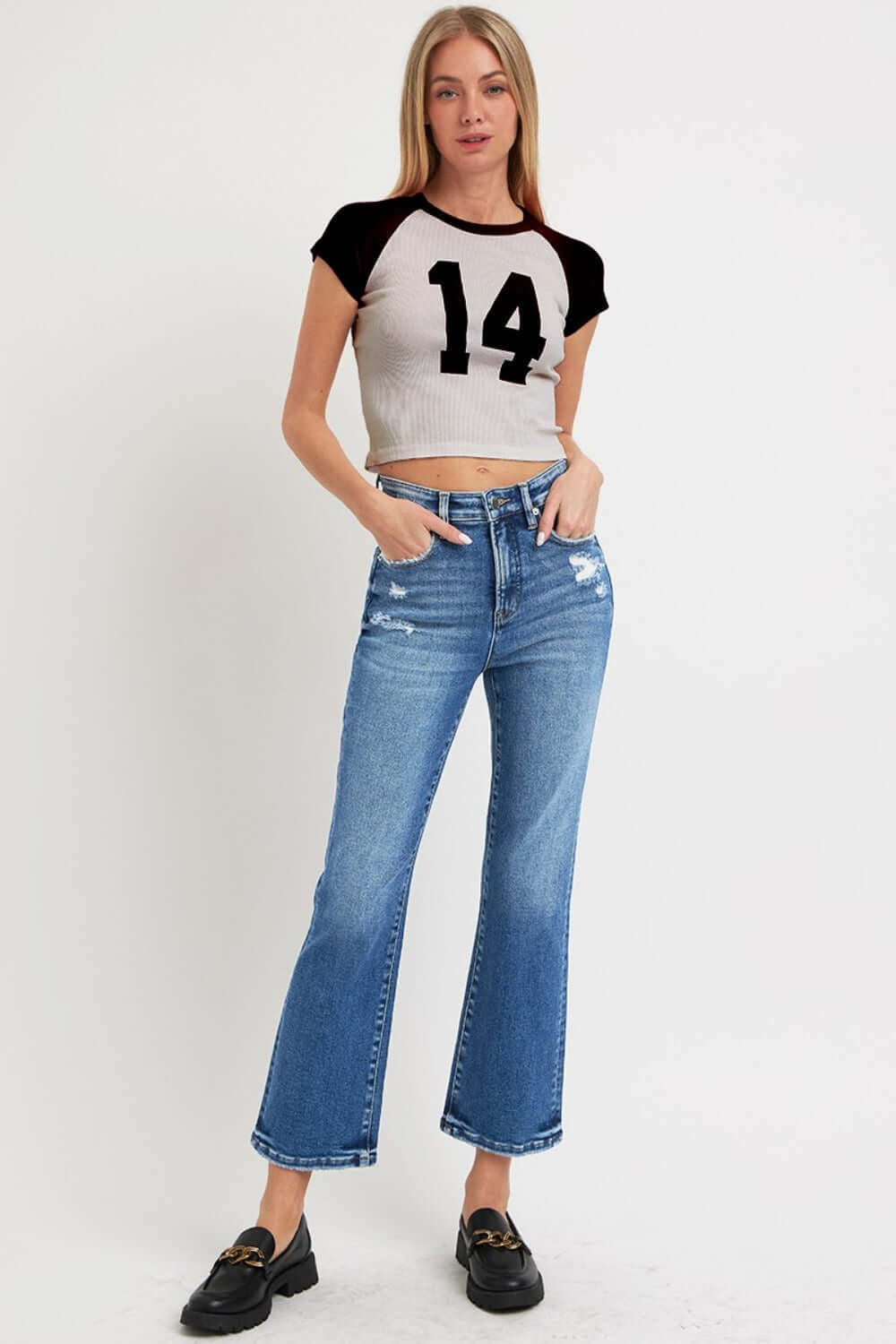 Model wearing RISEN Full Size Tummy Control High Rise Crop Bootcut Jeans with a black and white number 14 crop top