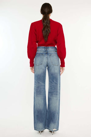 Rear view of distressed high waist bootcut jeans paired with a red sweater, showcasing retro-chic style and slightly washed stretch denim.