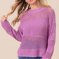 Woman wearing BiBi Openwork Long Sleeve Knit Top in purple with intricate openwork details and long sleeves, paired with jeans.