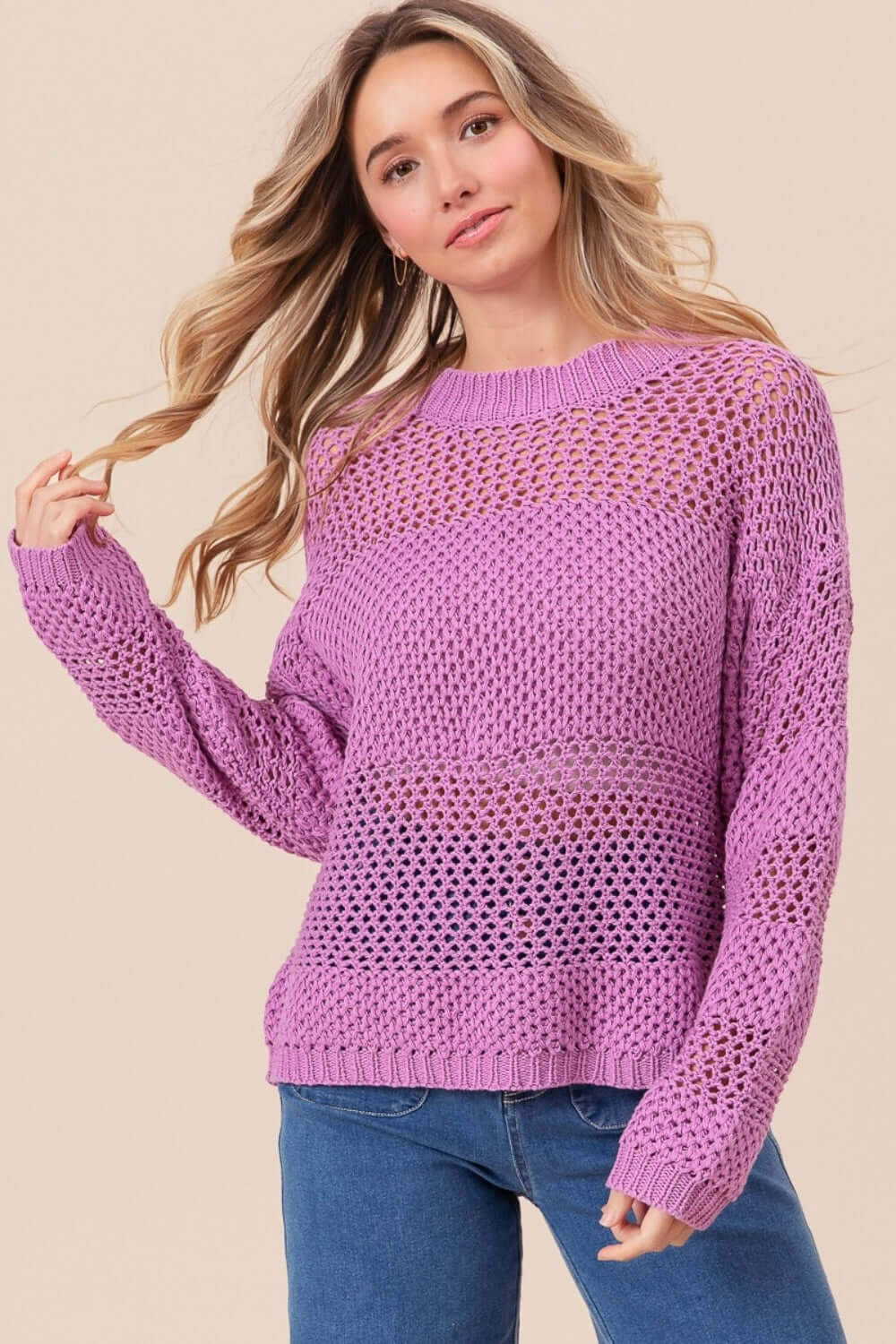 Woman wearing BiBi Openwork Long Sleeve Knit Top in purple with intricate openwork details and long sleeves, paired with jeans.